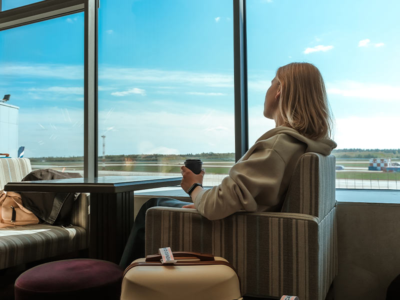 Frau entspannt am Flughafen mit Kaffee, wartend auf ihren Flughafentransfer in München.